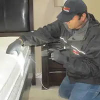 Bed bug inspection technician checking a mattress and bed frame for signs of infestation in Jersey City, NJ