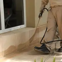 General pest control technician spraying exterior perimeter around a home in Jersey City, NJ