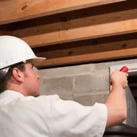 Termite inspection technician checking a basement wall and framing for termite activity in Jersey City, NJ