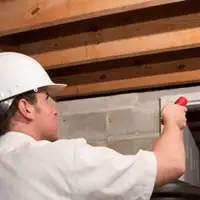 Termite inspection technician checking a basement wall and framing for termite activity in Jersey City, NJ